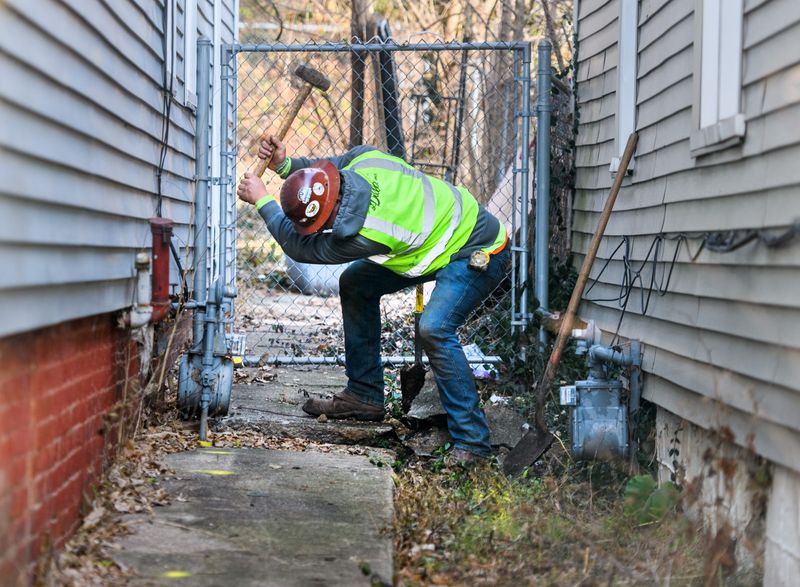 JC Dillon Plumbing laborer Lucas Reinbeck breaks up a section of concrete sidewalk to install a plastic water line, replacing the lead line to a house in South Peoria.