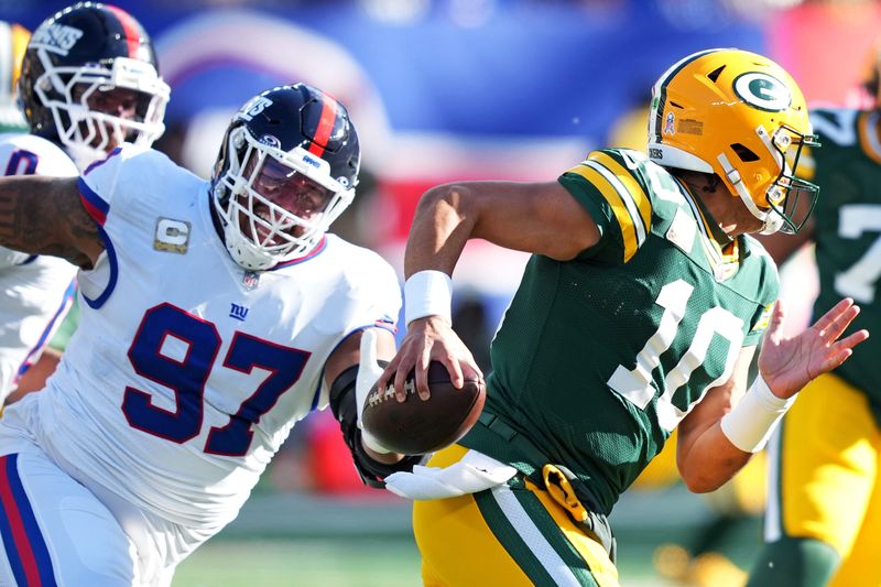 Nov 16, 2025; East Rutherford, New Jersey, USA; Green Bay Packers quarterback Jordan Love (10) scrambles away from New York Giants defensive tackle Dexter Lawrence II (97) during the first quarter at MetLife Stadium. Mandatory Credit: Robert Deutsch-Imagn Images