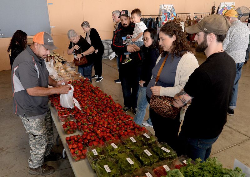 Customers gather around the Odelehr's Market table at the Illinois Product Farmers Market on Thursday, May 7, 2026, in Springfield.