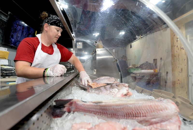 Carter's Fish Market employee Jessica Dougherty puts fish on ice at the market Thursday, June 18, 2026.