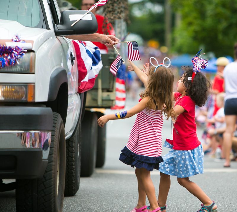 Aubrey Bennett-Chiffons (left), 4, of Hockessin and Jordan Chiffons, 4, of Newark reach for the American flags being passed out along Old Lancaster Pike in the Hockessin Fourth of July Parade in 2016.