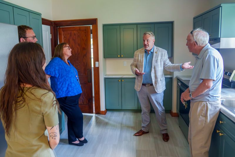 U.S. Rep. Eric Sorensen (D-IL), second from right, chats in the kitchen of a newly renovated home on Marquette Street that's part of the Reclaim Peoria affordable housing initiative during a tour and press conference Tuesday, July 7, 2026 in South Peoria. Sorensen toured the Neighborhood House social service facility before a press conference about the recent federal housing bill and the Peoria program.