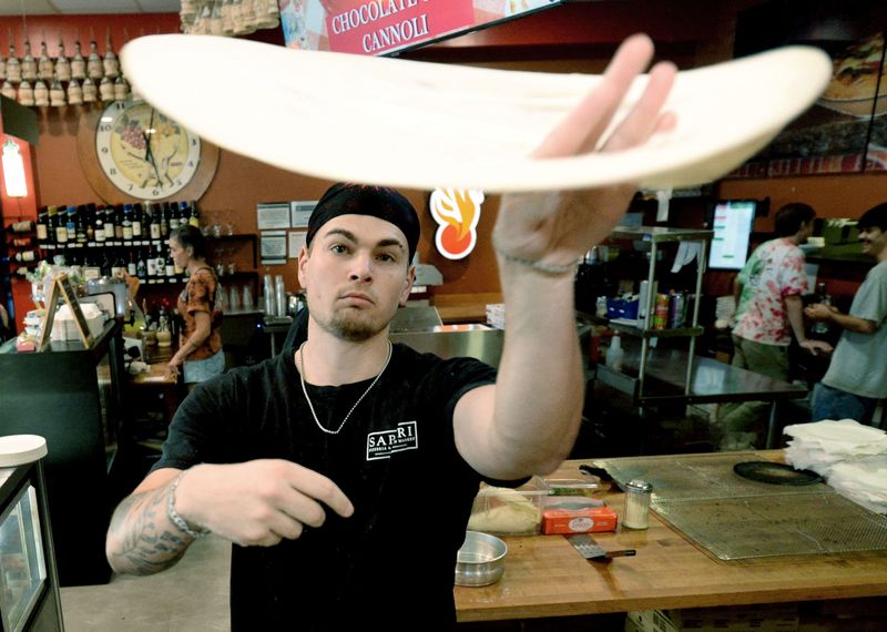 Pizza cook Eli Oldham tosses dough for a pizza at Sapori Pizzeria & Italian Market, Thursday, July 30, 2026.