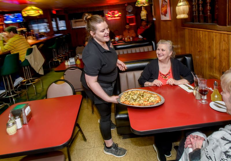 In this file photo, Agatucci's server Breeannah Burley delivers a pizza to customers at the popular longstanding Peoria restaurant at 2607 N. University Street.