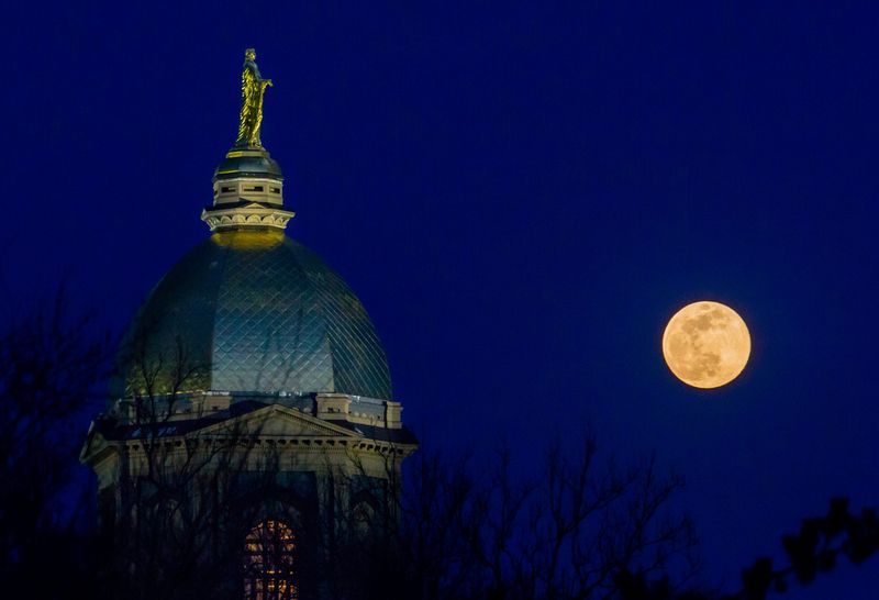 The super moon rises Tuesday, April 7, 2020 near the golden dome of the Administration Building on the campus of Notre Dame. The university Tuesday declined to say whether it will host a presidential debate after the University of Michigan announced it had canceled its debate because of coronavirus concerns.