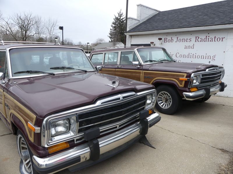 The twin wood-paneled Jeep Grand Wagoneers, one with a flat tire, sit in the lot at Bob Jones Radiator & Auto Repair, 923 S. Walnut St. (Laura Lane / Herald-Times)
