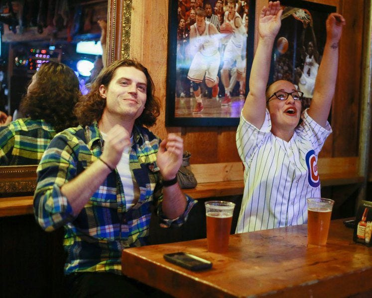 Cubs fans Chris Yarling, left, and Krystiana Krupa cheer at the Upstairs Pub Wednesday night as their team plays against the Cleveland Indians during the second game of the World Series.