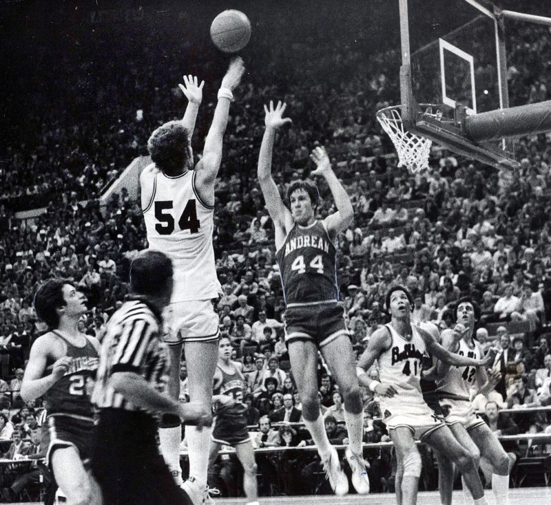 New Albany's Phil Benninger (54) holds the 59ers at bay with a baseline jumper for two points as Andrean's Ray Gough (44) rises in defense.