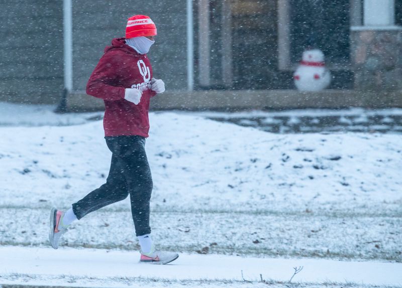 A fitness runner traverses a snowy path along Allisonville Road in Fishers, as about an inch of snow falls on central Indiana, Sunday, Jan. 23, 2022. A little more snow could fall Monday morning.