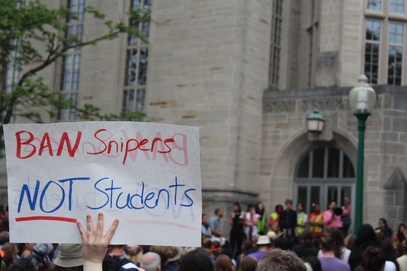 A protester holds up a sign saying 'Ban Snipers, Not Students' during the protest outside of Bryan Hall on Monday, April 29.
