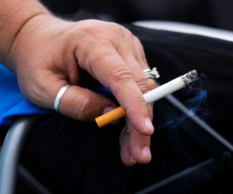 A fan puts down their cigarette while watching the Brickyard 400 from a viewing mound in turn four, Sunday, July 21, 2024, at Indianapolis Motor Speedway.