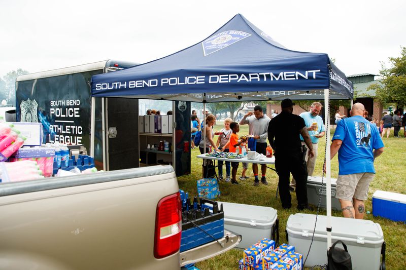 Members of the South Bend Police Department hand out food and drink during the department's back to school barbecue at Southeast Park on Friday, Aug. 2, 2024, in South Bend.