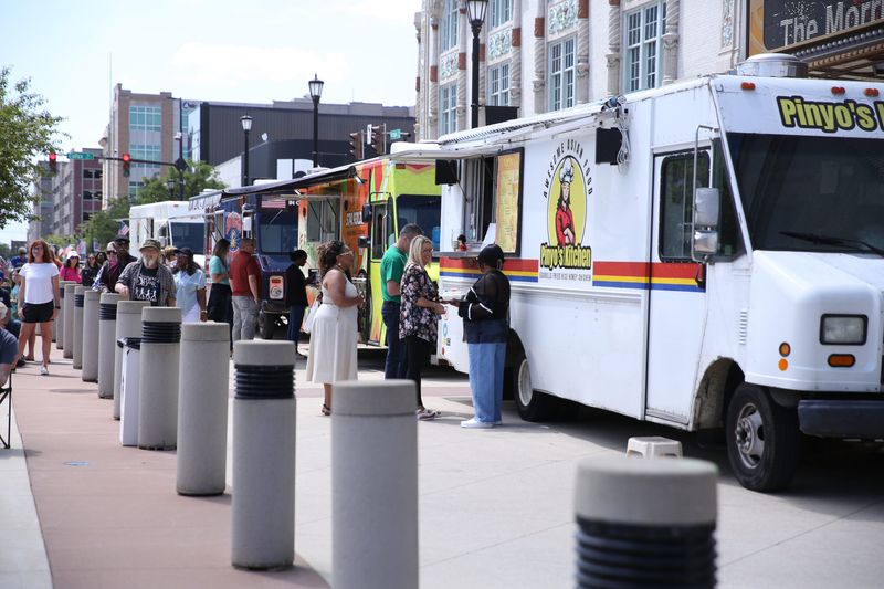 People lineup for the food trucks during Fridays by the Fountain on July 19, 2024, at the Jon R. Hunt Memorial Plaza outside the Morris Performing Arts Center in downtown South Bend. "Southside" Denny Snyder was the featured performer that day.