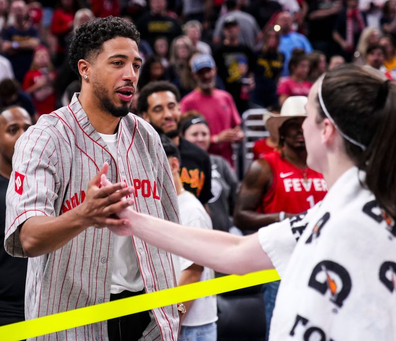 Indiana Pacers point guard Tyrese Haliburton high-fives Indiana Fever guard Caitlin Clark (22) on Friday, Aug. 16, 2024, after the game at Gainbridge Fieldhouse in Indianapolis.