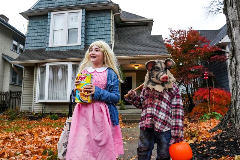 Kassidy Scheib, 11, and Chandler Deweese, 9, walk back to the sidewalk after receiving candy Thursday, Oct. 31, 2024, as families participate in trick-or-treating in Irvington east side of Indianapolis.