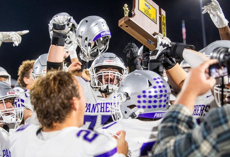 South's Junior Arellano (77) hoists the trophy after the IHSAA sectional final football game at Bloomington High School North on Friday, Nov. 8, 2024.