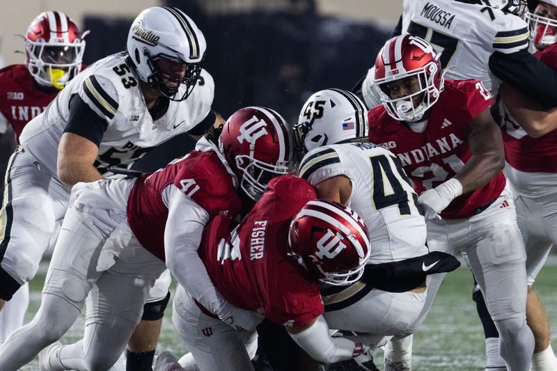 Nov 30, 2024; Bloomington, Indiana, USA; Purdue Boilermakers running back Devin Mockobee (45) runs the ball while Indiana Hoosiers linebacker Aiden Fisher (4) and defensive lineman Lanell Carr Jr. (41) defends in the second half at Memorial Stadium. Mandatory Credit: Trevor Ruszkowski-Imagn Images