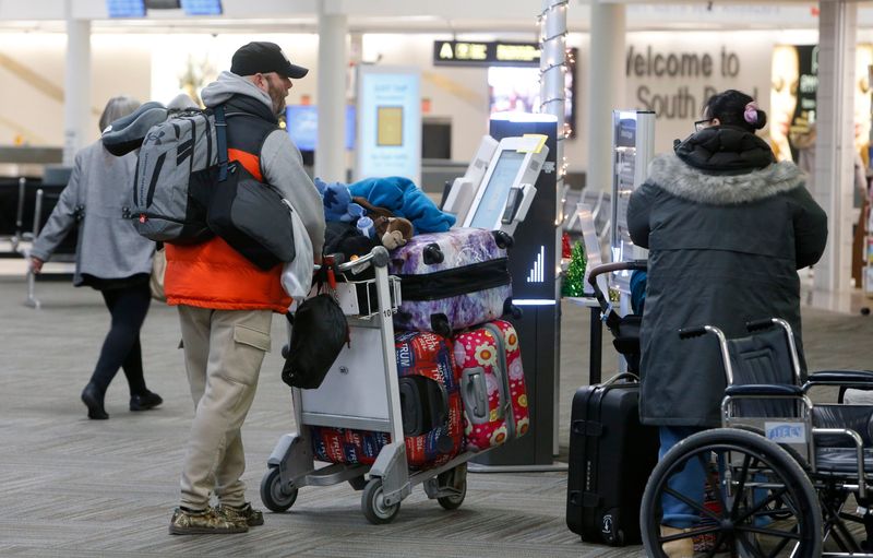 Passengers push their suitcases toward the ticket counter Monday, Dec. 23, 2024, at South Bend International Airport.