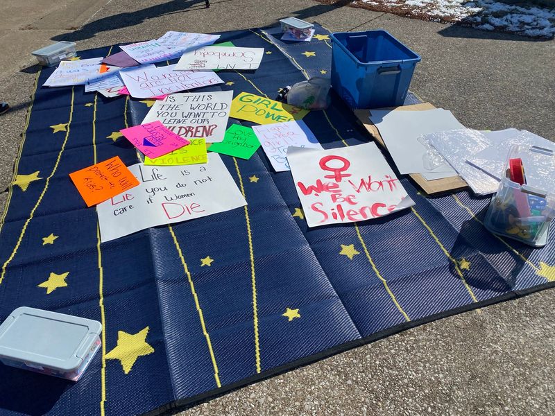 Signs lay on the ground available for protesters to pick up and use during the "No Kings Day" protest Monday, Feb. 17, 2025, at the Four Freedoms Monument in Evansville.