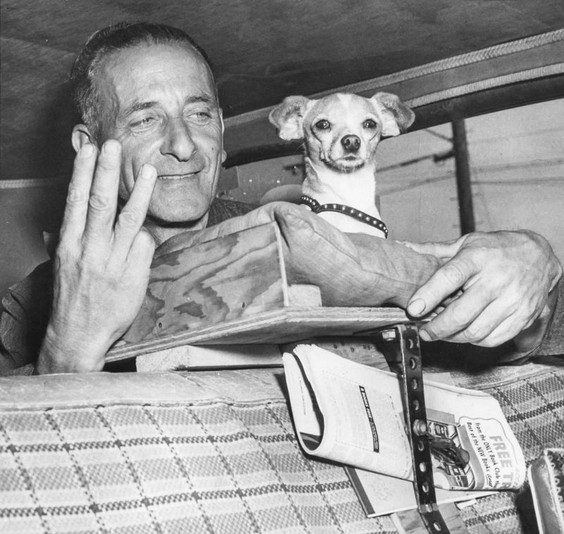Laurence “Larry” Bisceglia, 53, a mechanic from California, holds up a victory sign of three fingers Monday, April 30, 1951, symbolic of his third consecutive time at the “pole” position at Indianapolis Motor Speedway. With him is his dog, Wiggles, who has a special platform in Bisceglia 1933-model car.