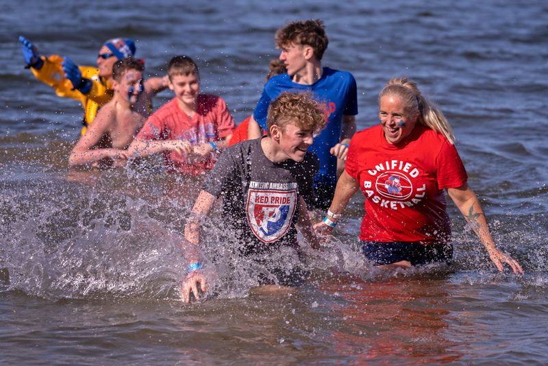 Plainfield Middle School’s Jason McDonalds, left, and Julie Pitcock join other plungers braving the cold waters during the Special Olympics Indiana High School Polar Plunge, Friday, Feb. 28, 2025 at Eagle Creek Park. More than 600 students from 18 Indiana high schools participated in the annual event. The Eagle Creek plunges also include one plunge for law enforcement and one for the community.