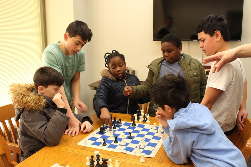Children test ideas on the chess board while coach Jimmy Brown quizzes them during a meeting of the Hoosier Chess Academy on March 3, 2025, at the Monroe County Public Library.