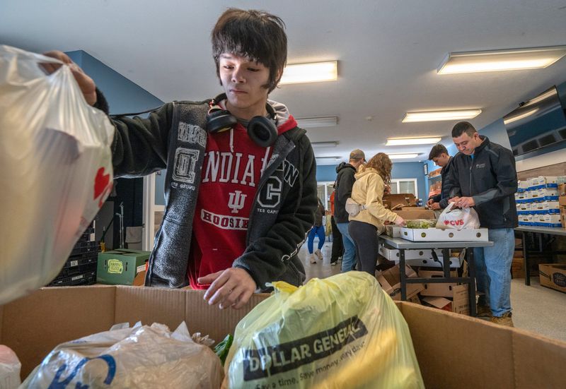 Misa Leon puts a filled bag of food gathered for distribution at the Lord’s Pantry at Anna’s House, Saturday, April 12, 2025.