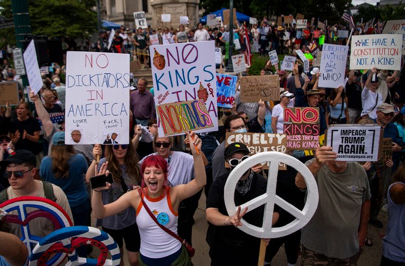 Protesters hold signs as they gather for the "No Kings" protest at the Monroe County Courthouse in Bloomington on Saturday, June 14, 2025.