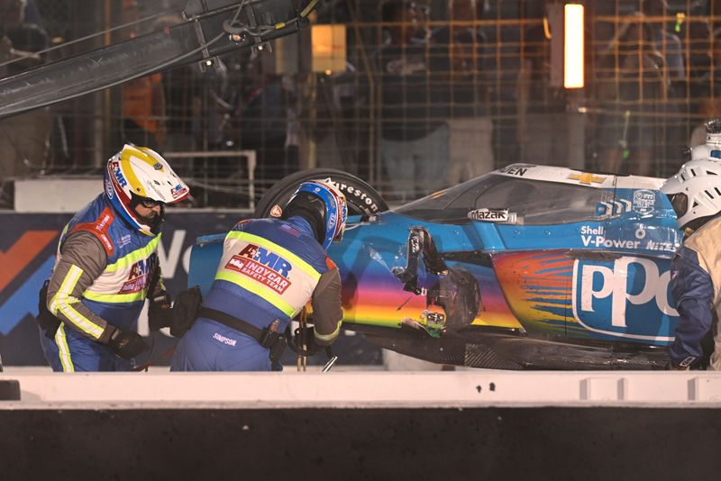 Jun 15, 2025; Madison, Illinois, USA; Members of the safety team hook up Team Penske driver Josef Newgarden (2) car to a tow truck after crashing during the Bommarito Automotive Group 500 at World Wide Technology Raceway.