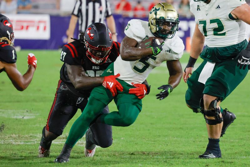 Nov 1, 2024; Boca Raton, Florida, USA; South Florida Bulls running back Nay'Quan Wright (5) runs the ball as Florida Atlantic Owls defensive lineman Devonta Davis (97) tries to make the tackle during the second half at FAU Stadium. Mandatory Credit: Reinhold Matay-Imagn Images