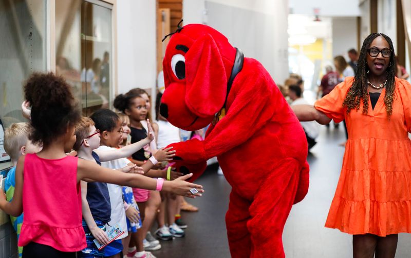 Clifford the Big Red Dog high-fives a line of students at Boyd Elementary School to celebrate literacy and reward elementary students with perfect attendance with a free book on Wednesday, June 25, 2025.