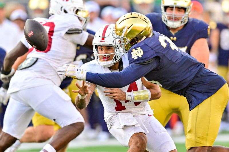 Oct 12, 2024; South Bend, Indiana, USA; Stanford quarterback Ashton Daniels (14) pitches the ball as he is hit by Notre Dame Fighting Irish defensive lineman Bryce Young (30) in the third quarter at Notre Dame Stadium. Mandatory Credit: Matt Cashore-Imagn Images