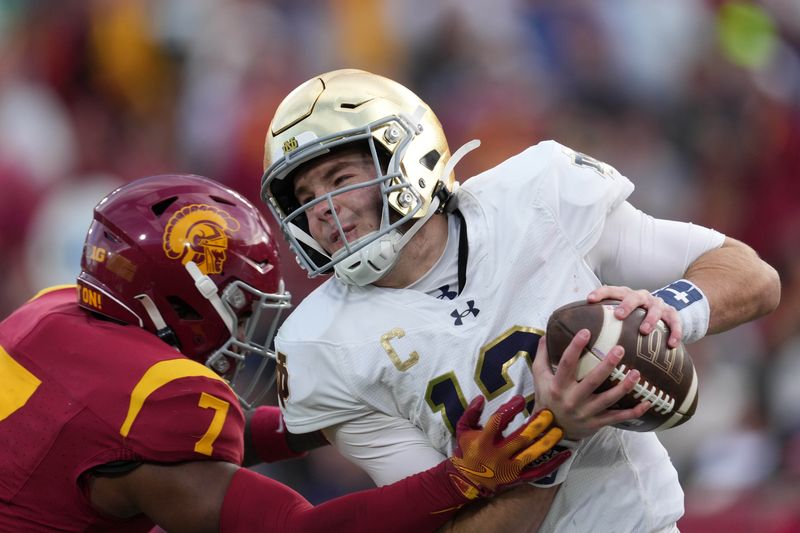 Nov 30, 2024; Los Angeles, California, USA; Notre Dame Fighting Irish quarterback Riley Leonard (13) is pressured by Southern California Trojans safety Kamari Ramsey (7) in the second half at United Airlines Field at Los Angeles Memorial Coliseum. Mandatory Credit: Kirby Lee-Imagn Images