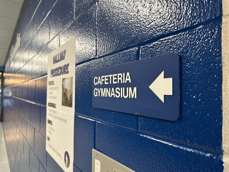 A sign points in the direction of a school's cafeteria and gymnasium.
