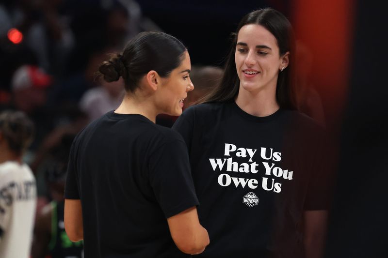 Team Clark guard Caitlin Clark (22) and Team Collier guard Kelsey Plum (10) wearing 'Pay Us What You Owe Us' shirts with the rest of the WNBA All-Stars to wArm up before the 2025 WNBA All Star Game at Gainbridge Fieldhouse.