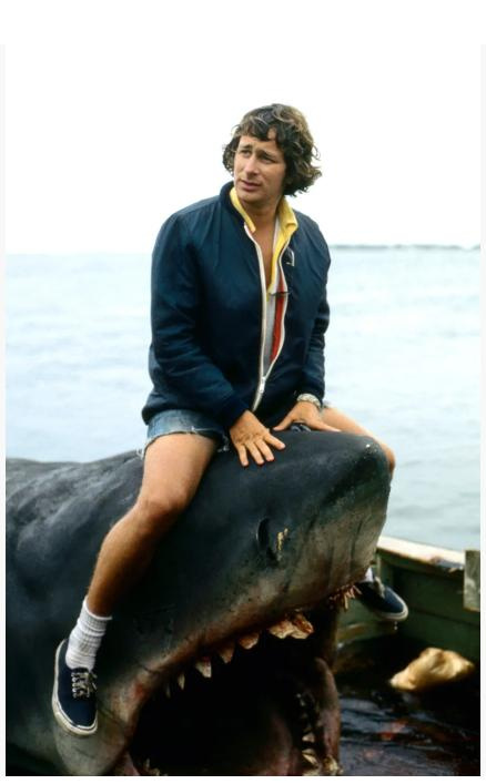 Director Steven Spielberg, perched on the mechanical shark during the filming of the movie "JAWS," the summer blockbuster that turns 50 this year.
