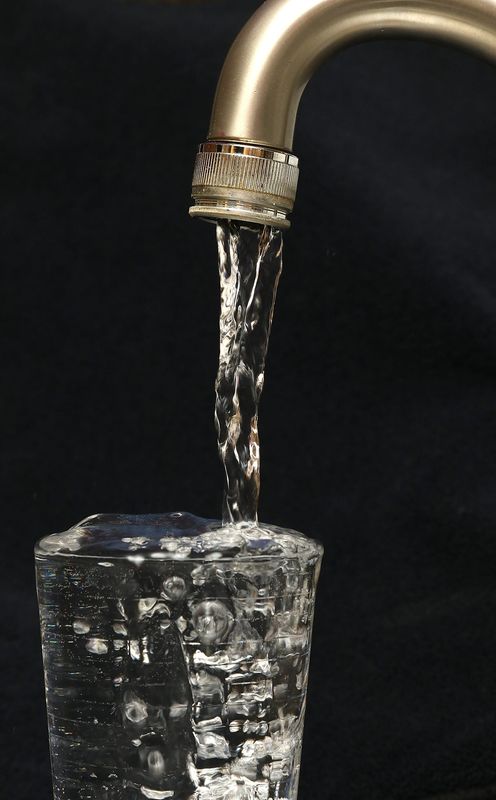 Water running from a faucet into a drinking glass.