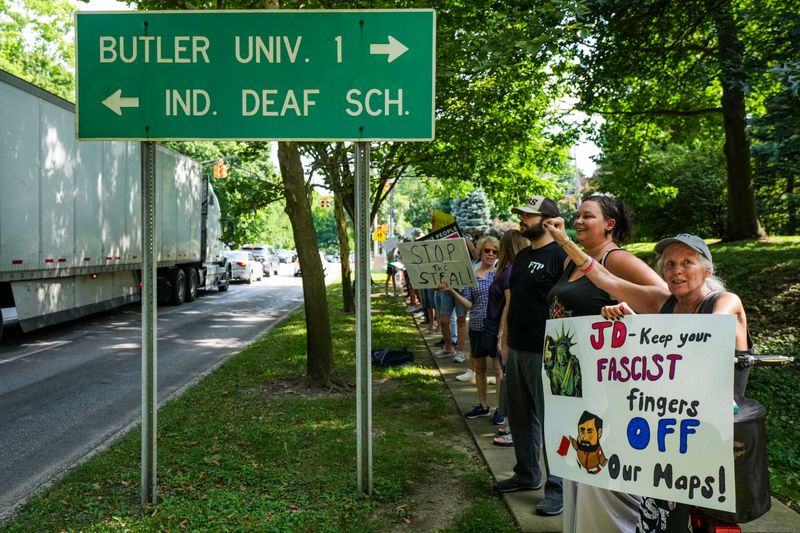 Elizabeth Buschmann of Carmel holds up a sign toward cars Thursday, Aug. 7, 2025, outside of the Indiana Governor’s residence on North Meridian Street in Indianapolis. Around 300 stood on the sidewalk to object to the idea of a special session for redistricting in Indiana.