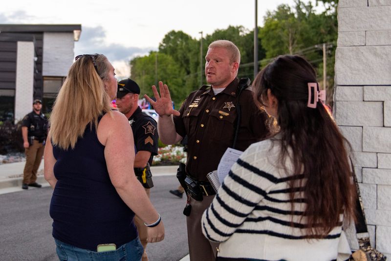 Kellie Moore (left) speaks with a Warrick County Sheriff's deputy in the aftermath of Lt. Gov. Micah Beckwith's chaotic town hall in Newburgh, Indiana, on Aug. 20, 2025.