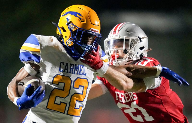Fishers' Atticus Finley (21) brings down Carmel's Andrew Pemberton (22) during the second half of a game Friday, Aug. 22, 2025, at Fishers High School.