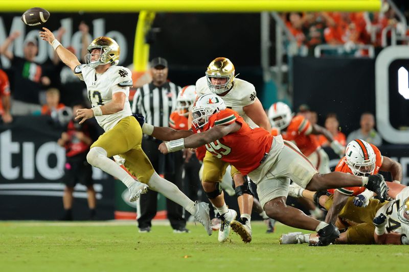 Aug 31, 2025; Miami Gardens, Florida, USA; Notre Dame Fighting Irish quarterback CJ Carr (13) throws the ball to avoid a sack against the Miami Hurricanes at Hard Rock Stadium. Mandatory Credit: Sam Navarro-Imagn Images