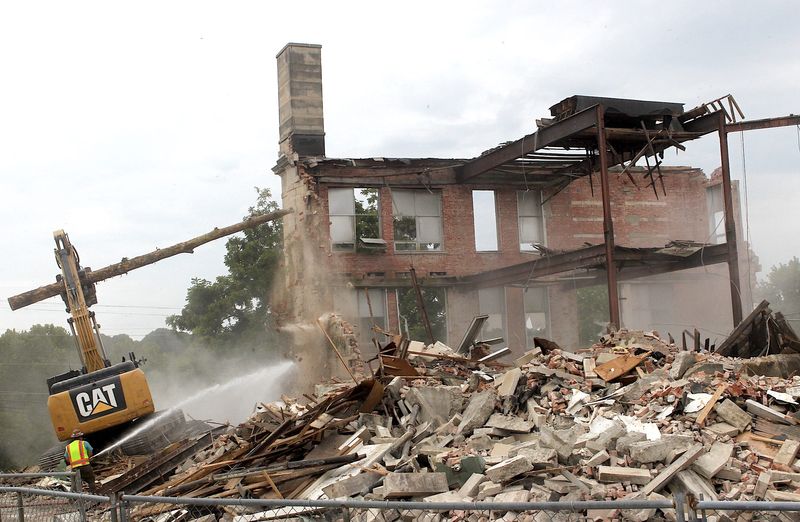 A shovel fitted with a long wooden pole serves as a battering ram to knock down the walls of Oolitic High School on Thursday, Aug. 28, 2025. The workers are employees of Robert Gilliland Excavating in Bloomington.