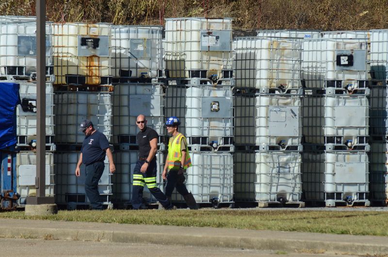 Officials walk past intact chemical containers while inspecting the site of a large fire at a PBTT Corp. manufacturing facility in Newburgh, Indiana, on Sunday, Sept. 7, 2025.
