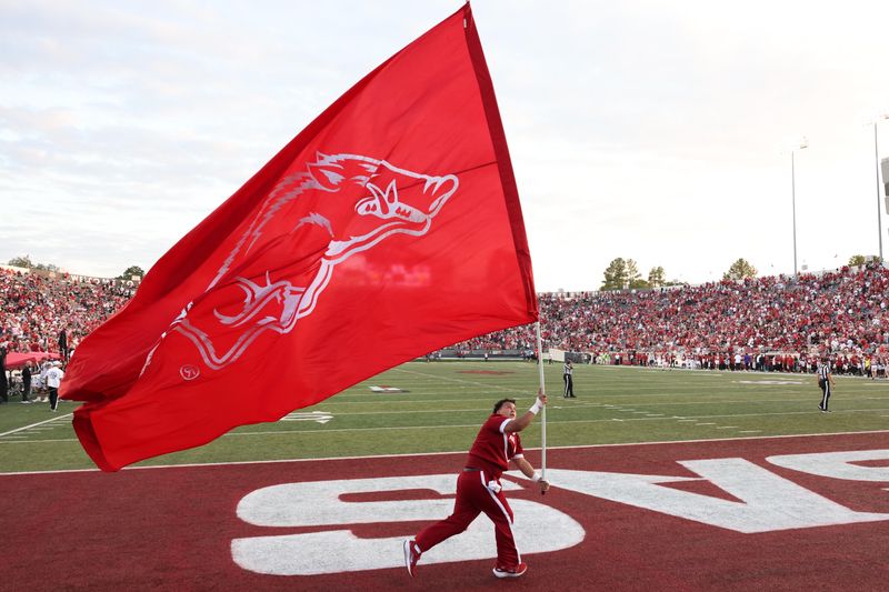 Sep 6, 2025; Little Rock, Arkansas, USA; Arkansas Razorbacks cheerleader waves a Razorbacks flag after a score in the fourth quarter against the Arkansas State Red Wolves at War Memorial Stadium. Arkansas won 56-14. Mandatory Credit: Nelson Chenault-Imagn Images