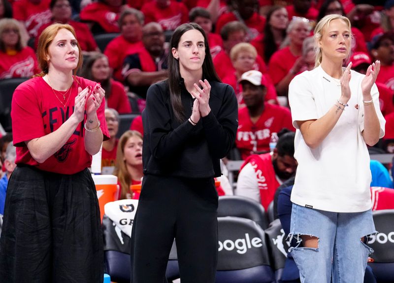 Indiana Fever forward Chloe Bibby (55), guard Caitlin Clark (22) and guard Sophie Cunningham (8) cheer during Game 4 of the WNBA semifinals on Sunday, Sept. 28, 2025, at Gainbridge Fieldhouse in Indianapolis. The Fever defeated the Aces 90-83.
