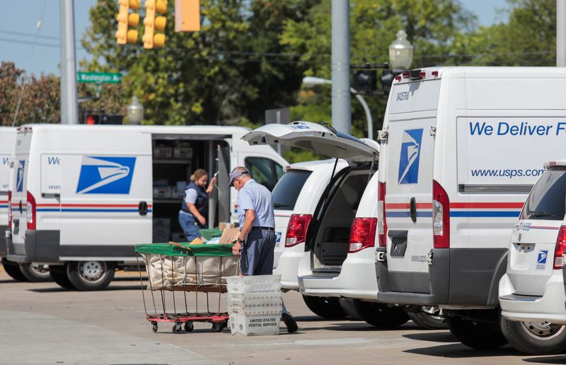 United States Postal Service (USPS) workers load mail into delivery trucks outside a post office in Royal Oak, Michigan, U.S. August 22, 2020.