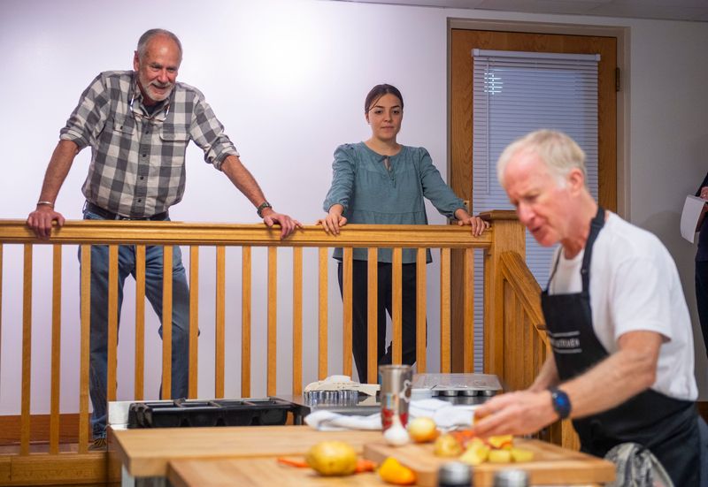 George Huntington, left, and Ava Collins watch as Steve Stroup cuts vegetables in the kitchen at In the Kitchen on Wednesday, Oct. 8, 2025.