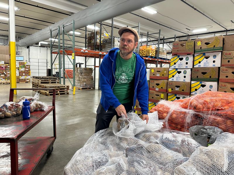 Justin Henry pulls bags of potatoes from a pallet inside the Food Finders Warehouse.