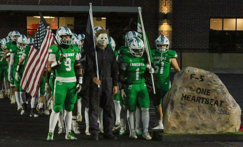 Concord football is joined by a student dressed as Michael Myers from the "Halloween" film franchise during pre-game introductions against Warsaw October, 31, 2025, in Mishawaka.