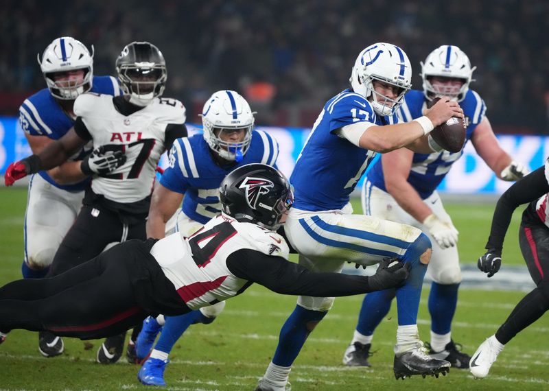 Nov 9, 2025; Berlin, Germany; Indianapolis Colts quarterback Daniel Jones (17) is tackled by Atlanta Falcons defensive tackle Brandon Dorlus (54) during the NFL Berlin Game at Olympic Stadium. Mandatory Credit: Kirby Lee-Imagn Images